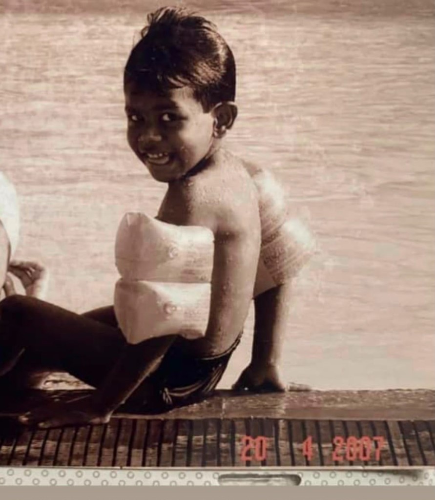 A childhood photo sitting by a pool with water wings, dated April 20, 2007.